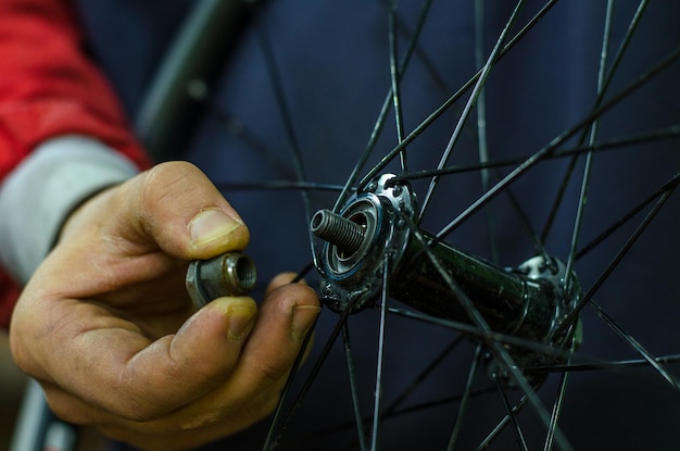 Reparação de bicicletas na oficina por um mecânico profissional Roda dianteira do cubo do anteparo Substituindo a graxa e os rolamentos de lavagem Cone na mão fechada