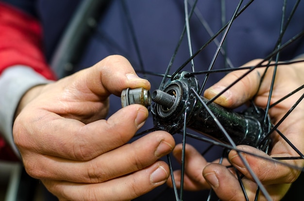 Foto reparação de bicicletas na oficina por um mecânico profissional roda dianteira do cubo do anteparo substituindo a graxa e os rolamentos de lavagem cone na mão fechada