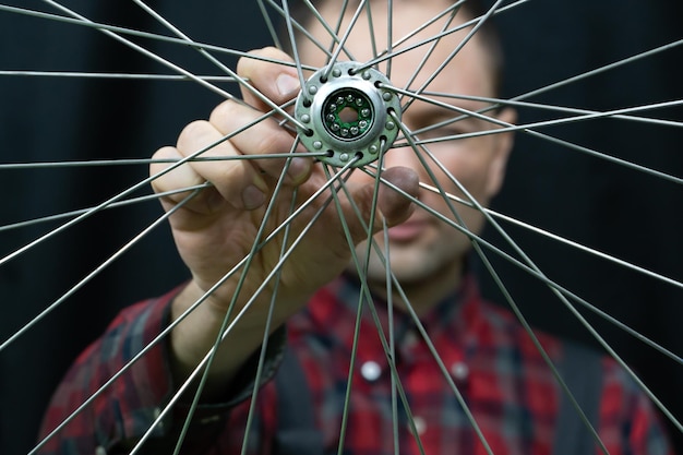 Reparação de bicicletas Um mecânico segura na mão a roda dianteira de uma bicicleta de estrada Manutenção do cubo substituição de graxa e rolamentos Rosto do mecânico no quadro