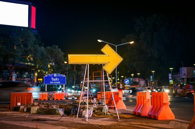 Foto reparação de estradas com sinal de seta amarela à noite