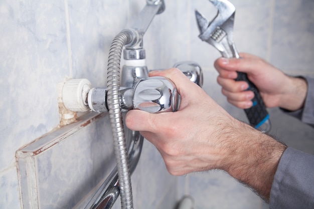 Foto reparação de homem e fixação da torneira do chuveiro no banheiro.
