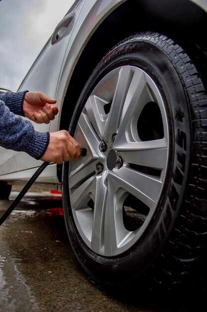 Foto reparação de inflação de pneus de carro a mão de um homem segura uma mangueira para fornecer ar para os pneus