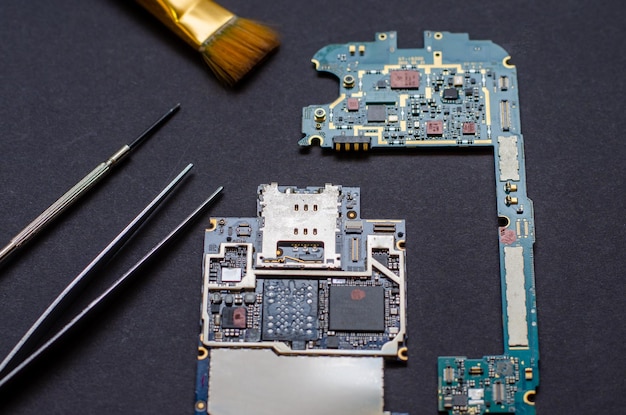 Reparação de telefones celulares e vários aparelhos eletrônicos O chip do dispositivo eletrônico está sobre a mesa em um fundo preto