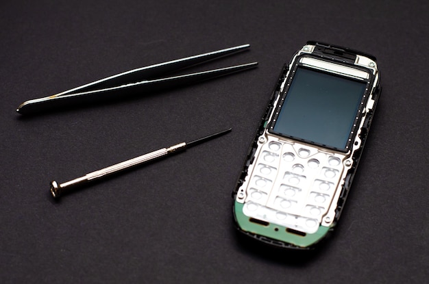 Foto reparação de telefones celulares e vários aparelhos eletrônicos um antigo telefone de botão na mesa do engenheiro