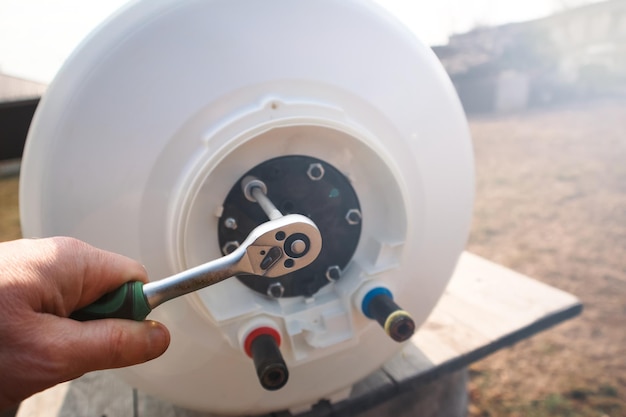 Foto reparação e manutenção de aquecedores de água de armazenamento um encanador desenrosca a flange da caldeira trabalhos de encanamento