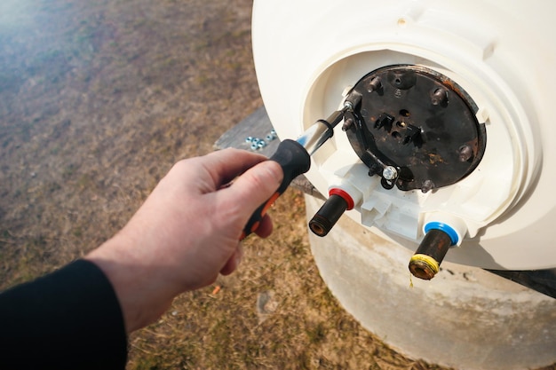 Foto reparação e manutenção de aquecedores de água de armazenamento um encanador desenrosca a flange da caldeira trabalhos de encanamento