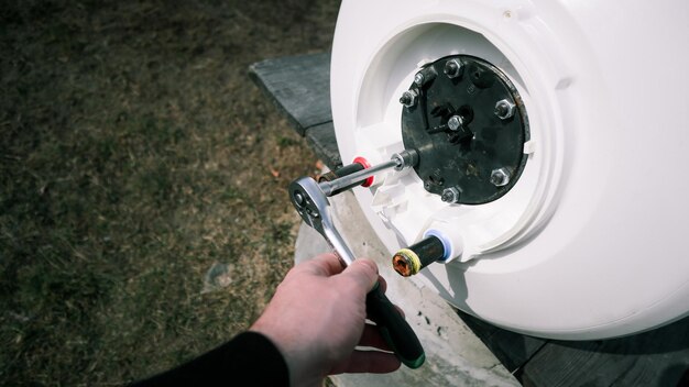 Foto reparação e manutenção de aquecedores de água de armazenamento um encanador desenrosca a flange da caldeira trabalhos de encanamento