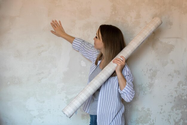 Foto reparação e melhoria da casa. uma linda garota tem papel de parede em suas mãos