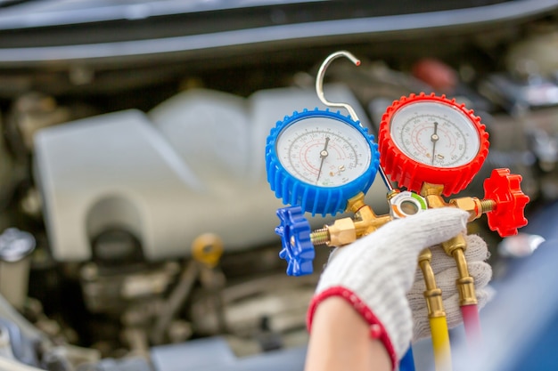 Reparación de aire acondicionado, reparador sosteniendo la herramienta del monitor para verificar y fijo el sistema de aire acondicionado del automóvil, técnico que verifica la recarga de refrigerante del sistema de aire acondicionado del automóvil