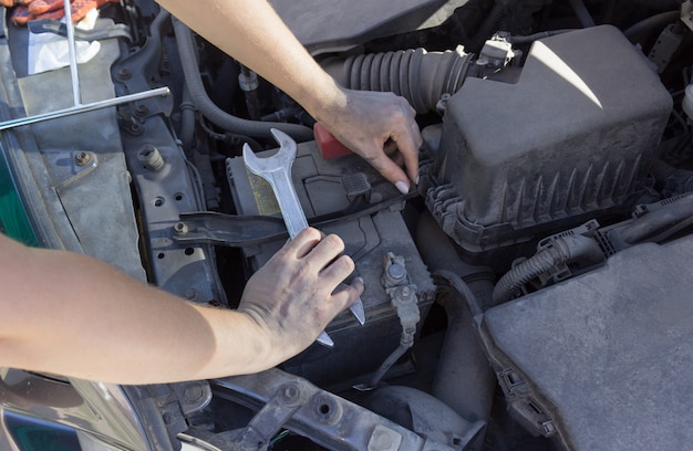 Reparación de la batería del automóvil debajo del capó, reparación de automóviles de manos femeninas