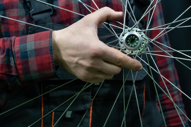 Reparación de bicicletas Un mecánico sostiene en su mano la rueda delantera de una bicicleta de carretera Mantenimiento del cubo reemplazo de grasa y rodamientos