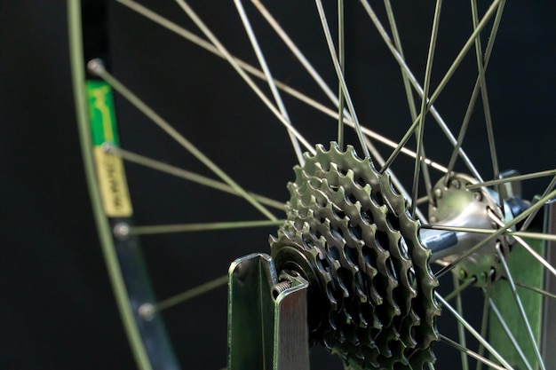 Reparación de bicicletas La rueda trasera está sobre un soporte sobre un fondo negro Primer plano de la llanta y el casete El mecánico nivela la rueda en el taller Soporte de alineación de ruedas Bicicleta fotografiada en el estudio