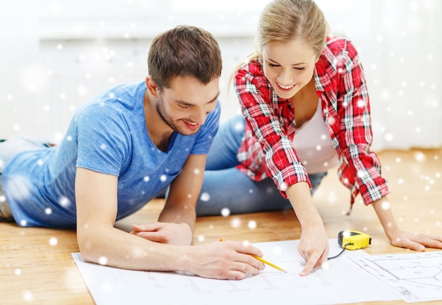 Foto reparación, construcción, renovación y concepto de personas - pareja sonriente mirando planos en casa