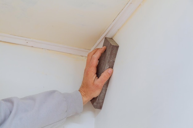 Reparación de habitaciones lijado a mano de la pared con una esponja de lijado lijado de la pared