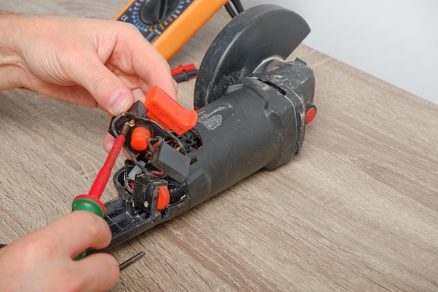 Reparación de herramientas eléctricas Un ingeniero reparando una fresadora angular El ensamblaje de la herramienta en el proceso de reparación