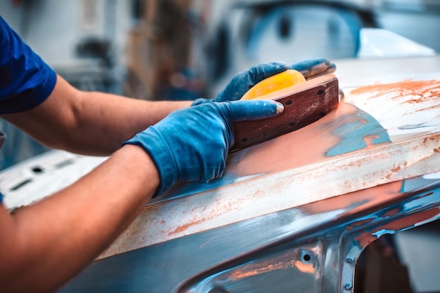 Reparación mecánica de pintura corporal Un mecánico repara un automóvil después de un accidente Lije la imprimación antes de pintar