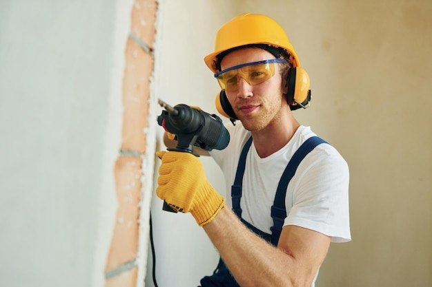 Reparación moderna Joven trabajando en uniforme en la construcción durante el día