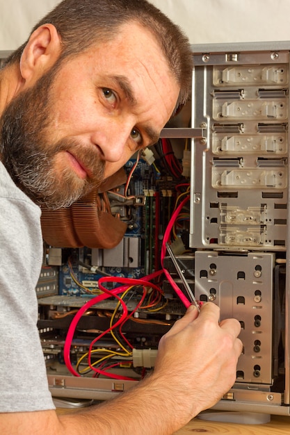Reparación de ordenador. un hombre con barba arreglando la unidad del sistema