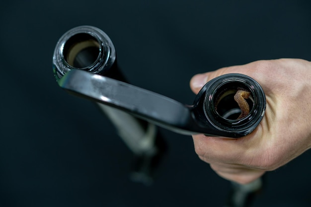 Reparación profesional de bicicletas en el taller El mecánico repara las juntas de aceite de cambio de aceite de horquilla de suspensión Piezas de horquilla de bicicleta sobre un fondo negro en el taller