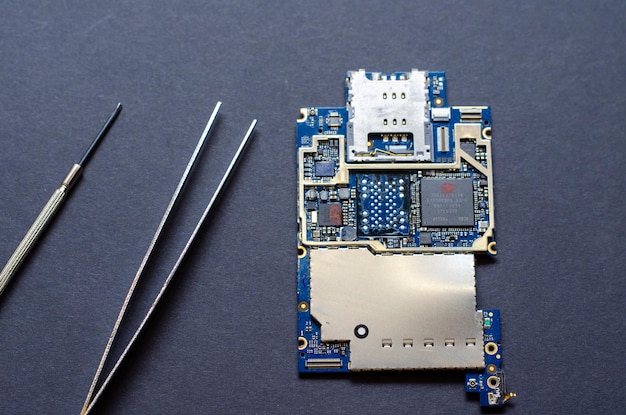 Reparación de teléfonos móviles y varios aparatos electrónicos El chip del dispositivo electrónico se encuentra sobre la mesa sobre un fondo negro