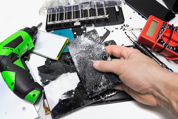 Reparación de teléfonos en un taller, pantalla rota del teléfono, preparación para reemplazar la pantalla del teléfono