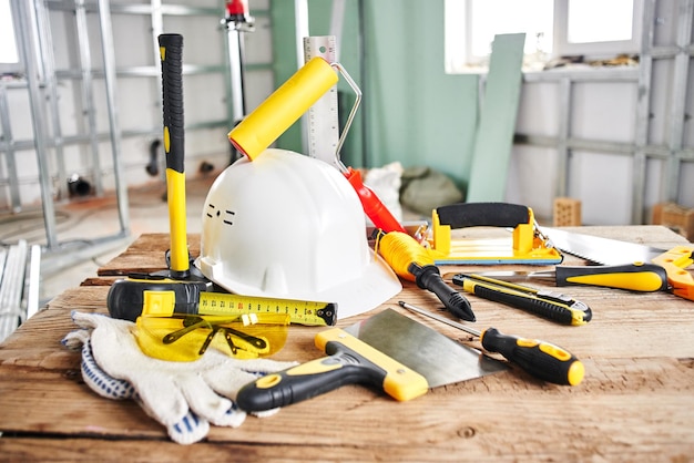 Reparaciones en el hogar. Herramientas de construcción, ladrillos y casco en la mesa de madera.