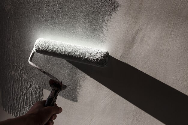 Reparaciones del hogar. Pintar las paredes de la habitación en gris con un rodillo de pintura.