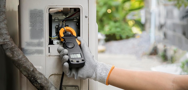 Reparador de aire acondicionado usando medidor de electricidad para comprobar el funcionamiento del aire acondicionado.