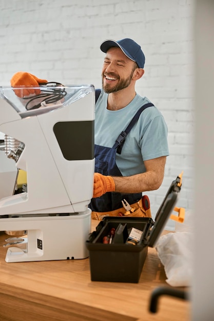 Reparador alegre consertando máquina de café no café