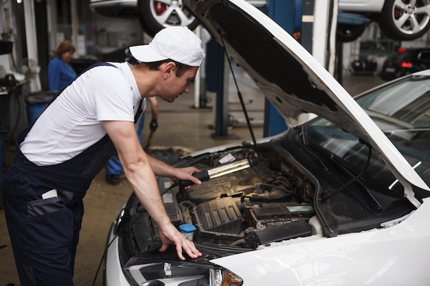 Reparador de automóviles con experiencia examinando el motor de un coche