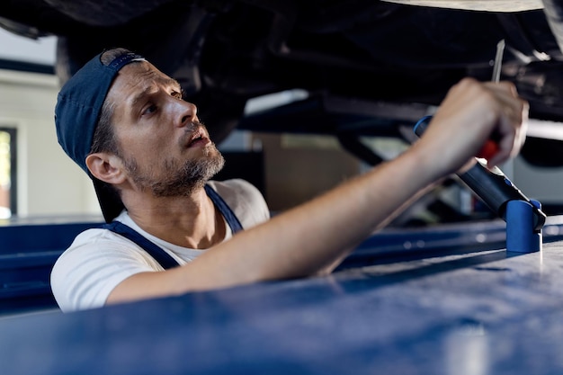 Reparador de automóviles trabajando debajo de un vehículo en un taller