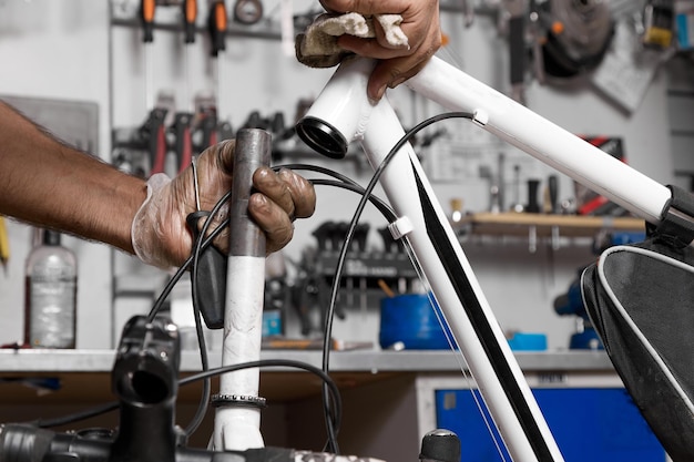 Reparador de bicicletas con guantes protectores desmonta la columna de dirección para limpiarla