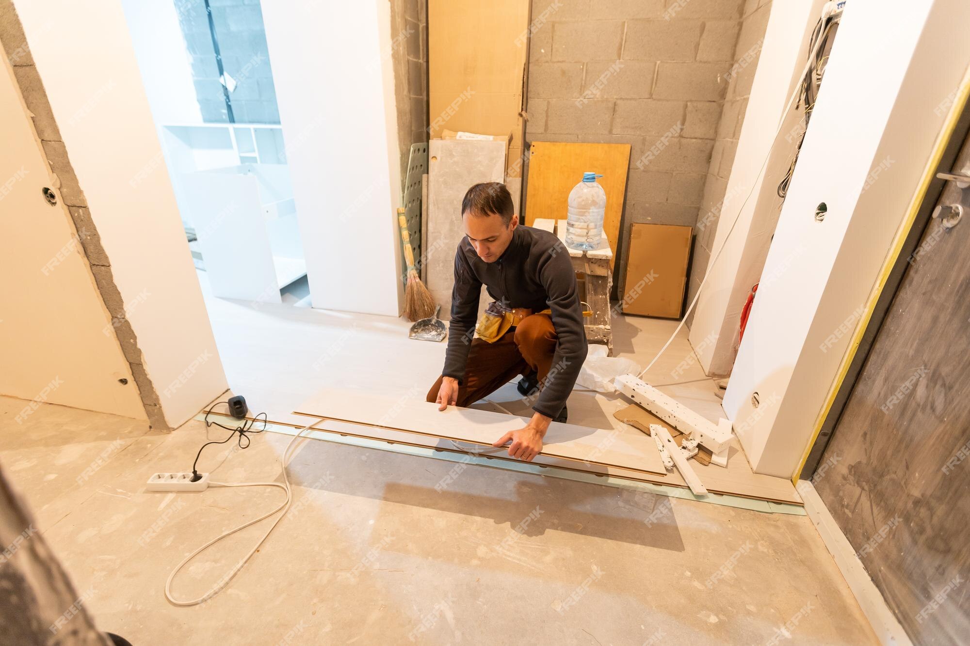 Reparador colocando pisos laminados en casa.