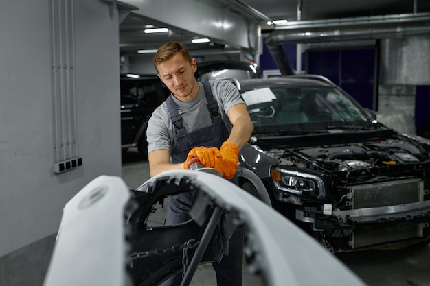 Reparador com lixadeira removendo carro antigo de pintura