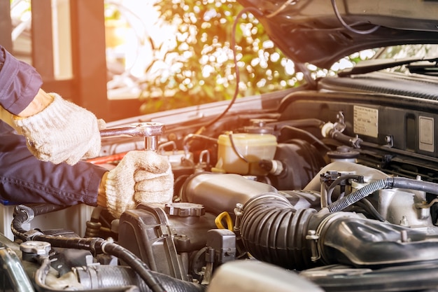 Reparador de carro, arrancando o motor de um carro que entrou em serviço em uma oficina de reparação automóvel