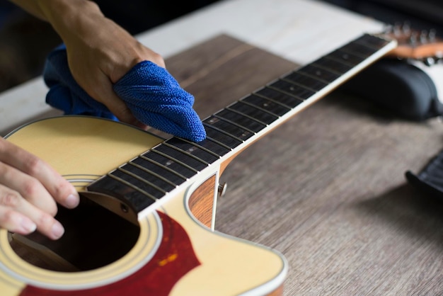 El reparador de guitarras está limpiando la guitarra acústica Paño limpio para limpiar el diapasón Primer plano