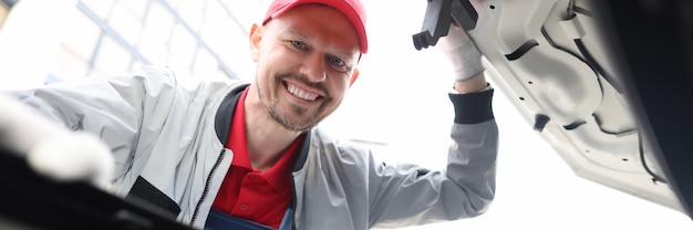 Reparador de hombre mirando debajo del capó del coche