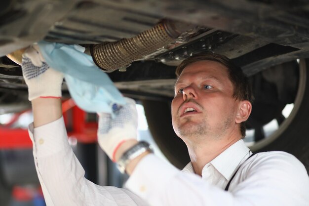 Reparador de hombre reparando coche bajo el capó en la estación de servicio