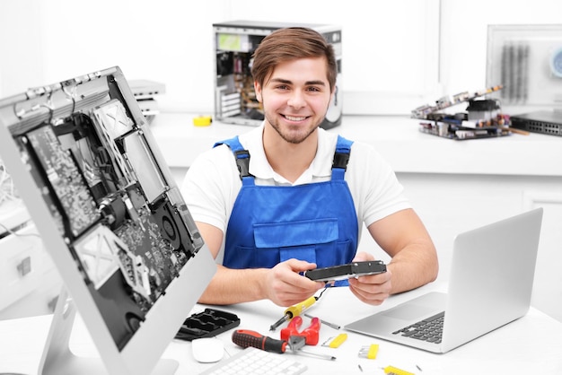 Foto reparador joven con monitor de computadora desmontado en el centro de servicio