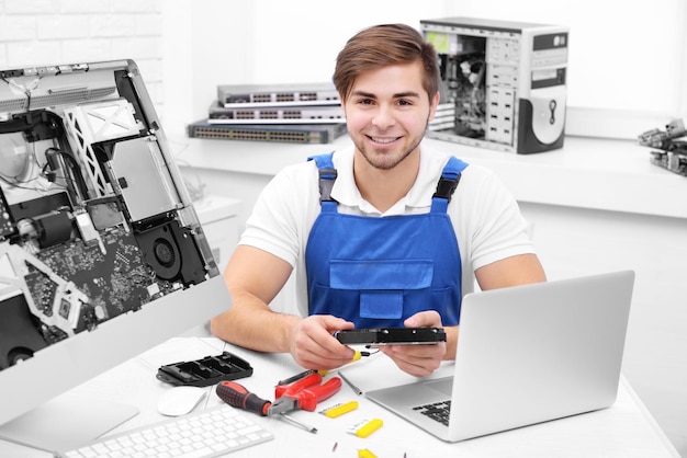 Foto reparador joven con monitor de computadora desmontado en el centro de servicio