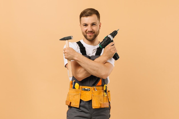 Foto reparador masculino positivo en casa con herramientas sobre fondo beige