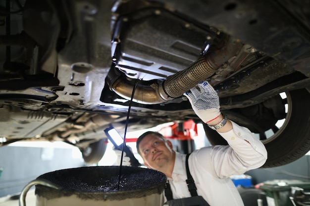 Reparador mecânico de automóveis inspecionando o motor do carro na garagem da estação de serviço