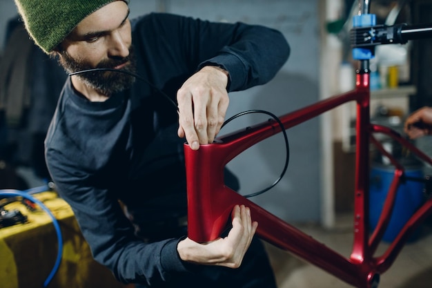 Reparador mecánico ensamblando cables de freno de bicicleta personalizados en el taller