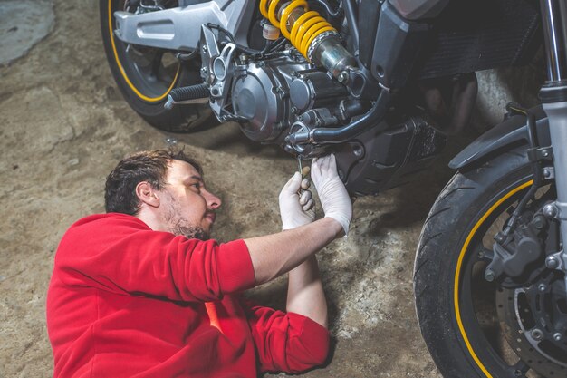 Reparador mecânico fazendo manutenção ou conserto, consertando a motocicleta, motocicleta, centro de serviço