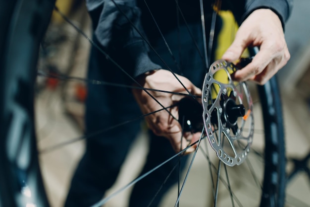 Reparador mecánico montando frenos de disco de rueda de bicicleta personalizada en taller