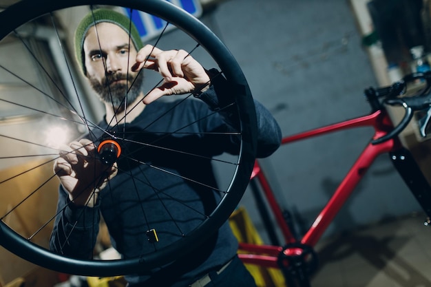 Reparador mecánico montando rueda de bicicleta personalizada en taller