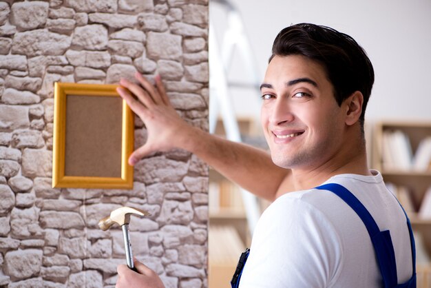 Foto reparador poniendo marco en la pared