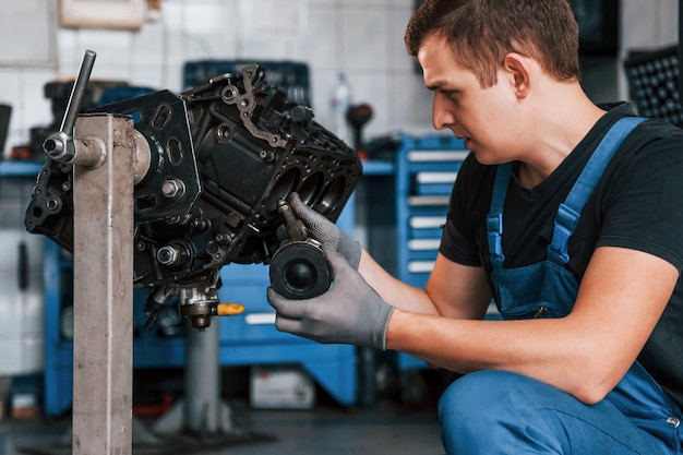 Reparador profesional en obras de garaje con motor de automóvil roto