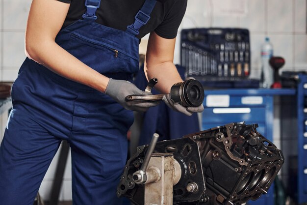 Reparador profissional na garagem trabalha com motor de automóvel quebrado