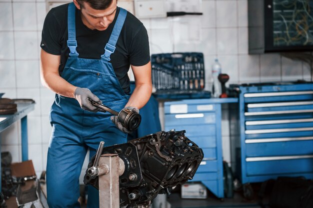 Reparador profissional na garagem trabalha com motor de automóvel quebrado